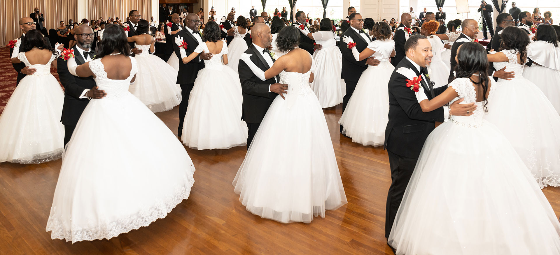 Image of young debutante ladies in white dresses performing.